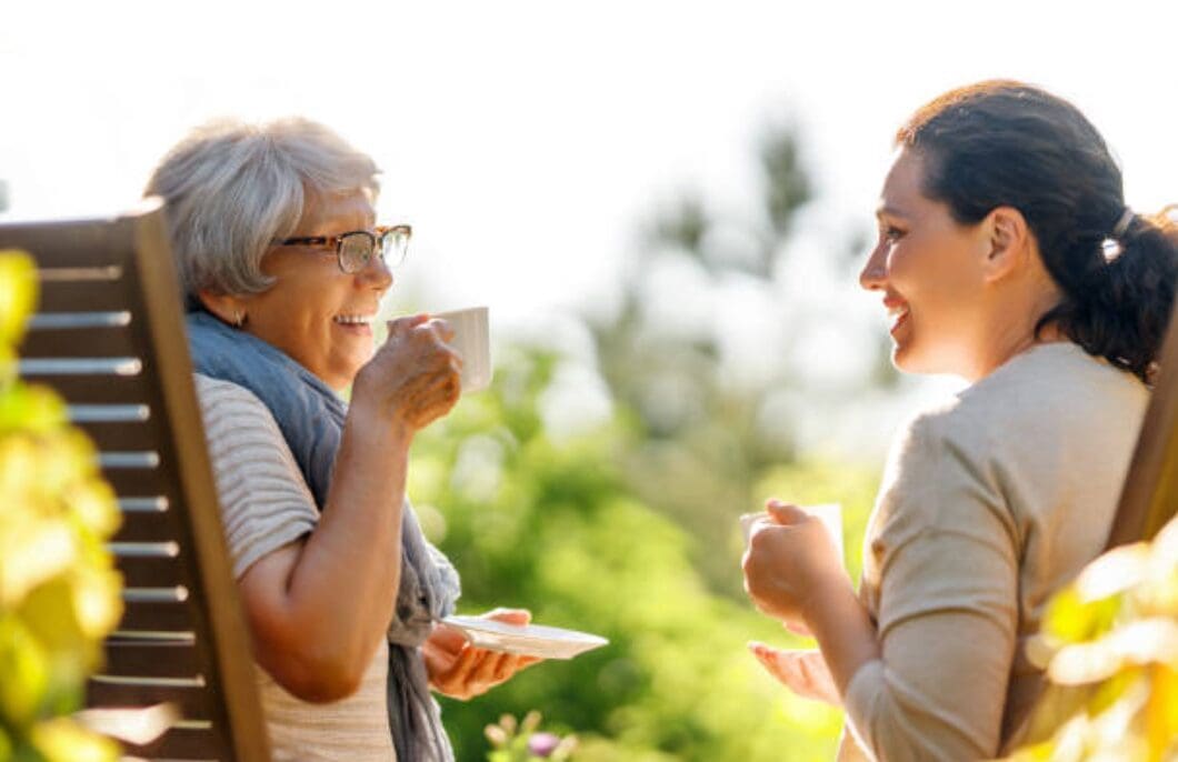 Caregiver Agency Caregiver having tea with and elderly lady